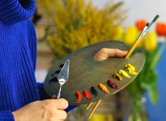 artist holding palette with different colors of paint