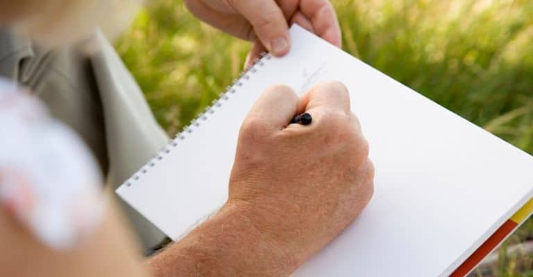 An artist drawing with pencil in sketchbook to take down sketching ideas