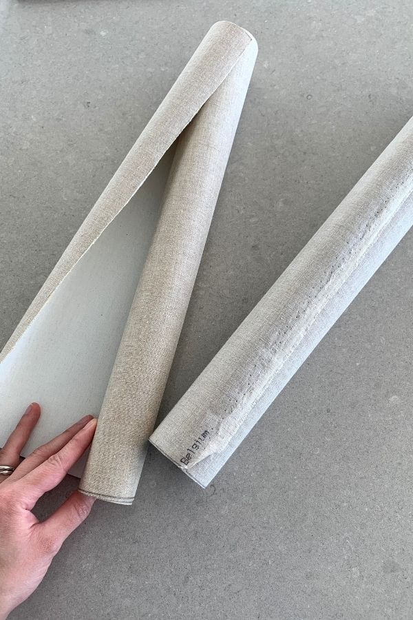 a hand with two rolled up canvas art supplies ready for travel