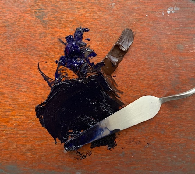 A palette knife mixing colors on a palette board, to use for a painting sketch