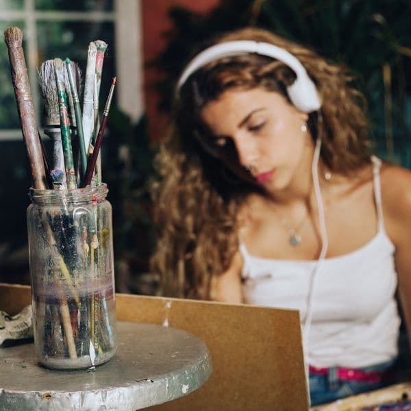 girl listening to music as she works on her daily painting habit