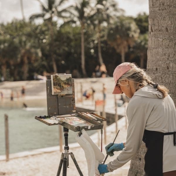 individual working on her painting habit by painting palm trees in the tropics