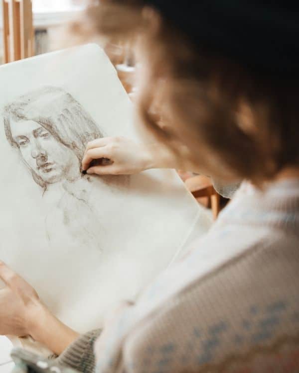 woman working on portrait drawing idea using charcoal and paper