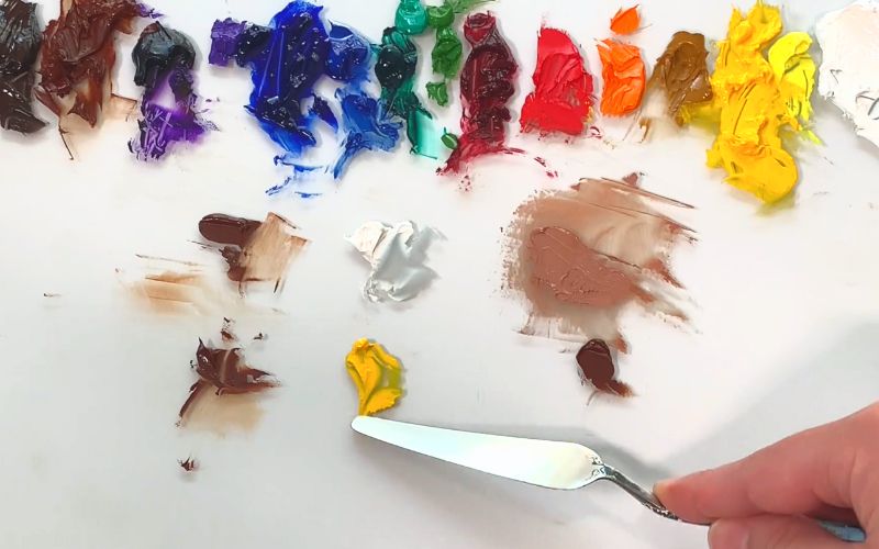 artist showing how to make brown paint colors light on palette