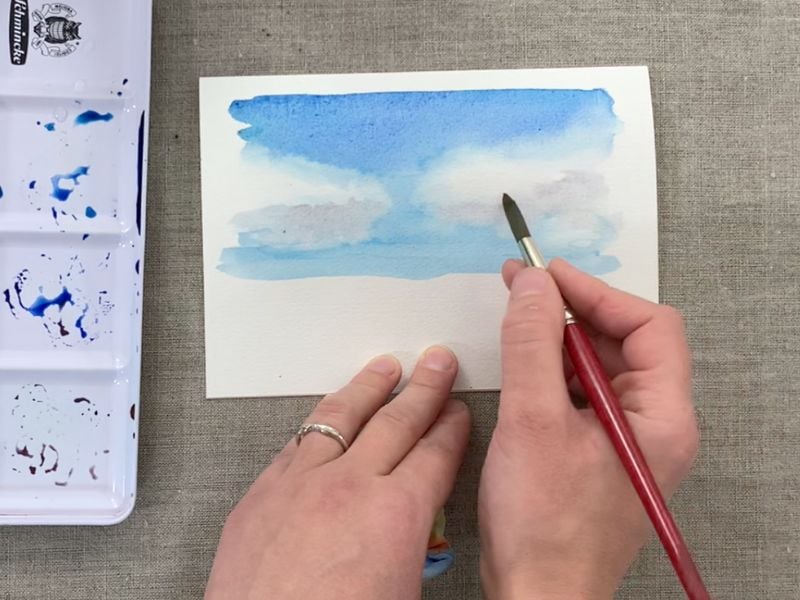 artist creating clouds of watercolor landscape painting