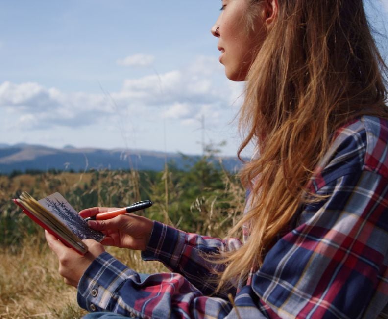 young girl using quick sketching to capture landscape inspirations in her sketchbook