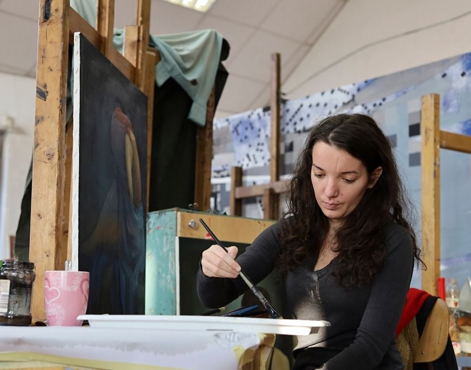 Young woman painting in a studio classroom improving through painting exercises